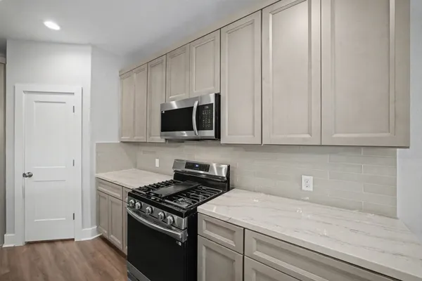 a kitchen with granite countertop white cabinets and black appliances