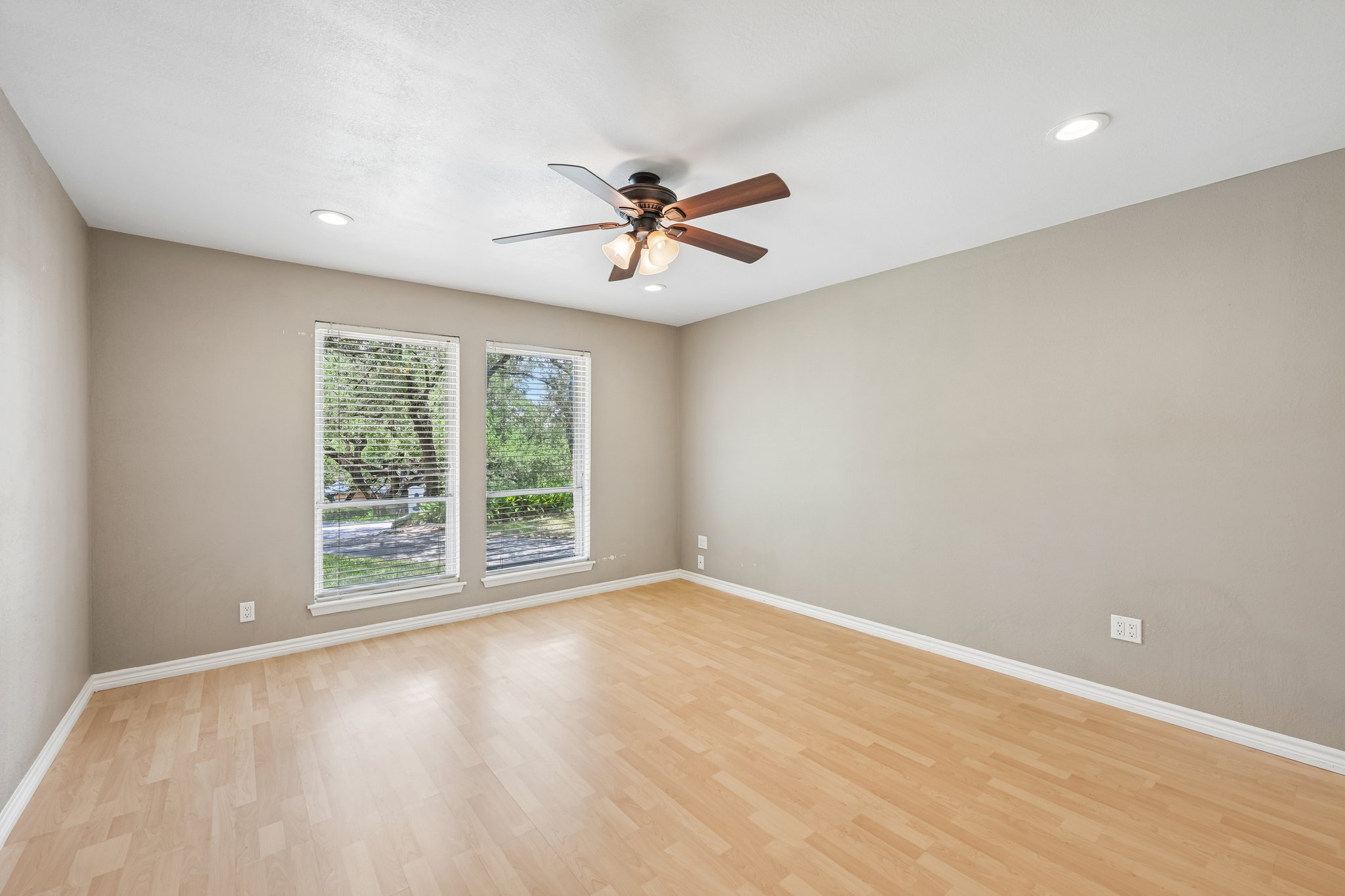 13101 Travis View Loop Austin, TX 78732 - Photo 13 of 27 A naturally illuminated room features light wood-look flooring and a classic ceiling fan, offering a versatile space.