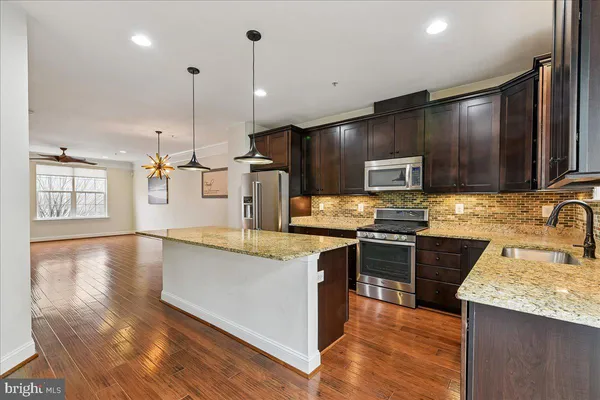 a kitchen with stainless steel appliances granite countertop a refrigerator a stove oven and a refrigerator with wooden floor