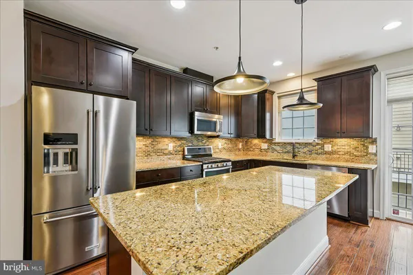 a kitchen with kitchen island granite countertop wooden cabinets and refrigerator