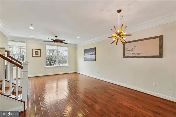 a view of a livingroom with wooden floor a ceiling fan and windows