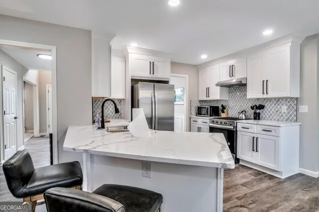 a kitchen with a sink stainless steel appliances and white cabinets