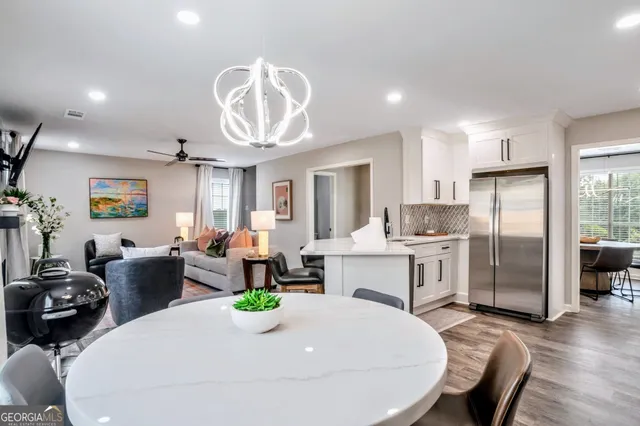 a very nice looking dining room with kitchen island furniture a refrigerator a sink and a dining table