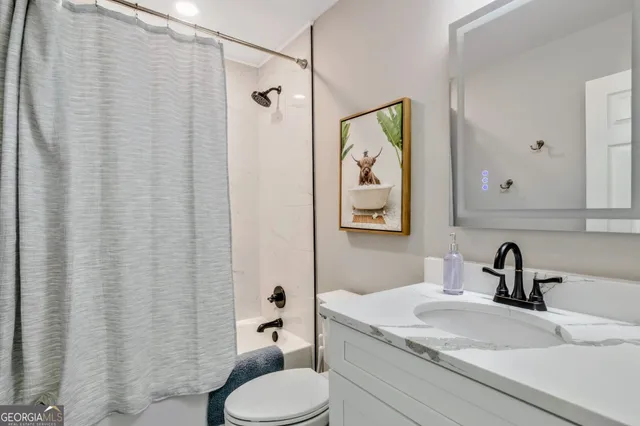 a bathroom with a granite countertop sink and a toilet