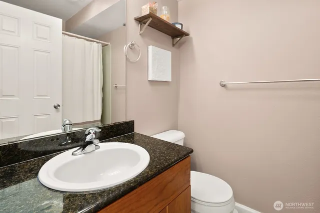 a bathroom with a granite countertop sink a mirror and a toilet