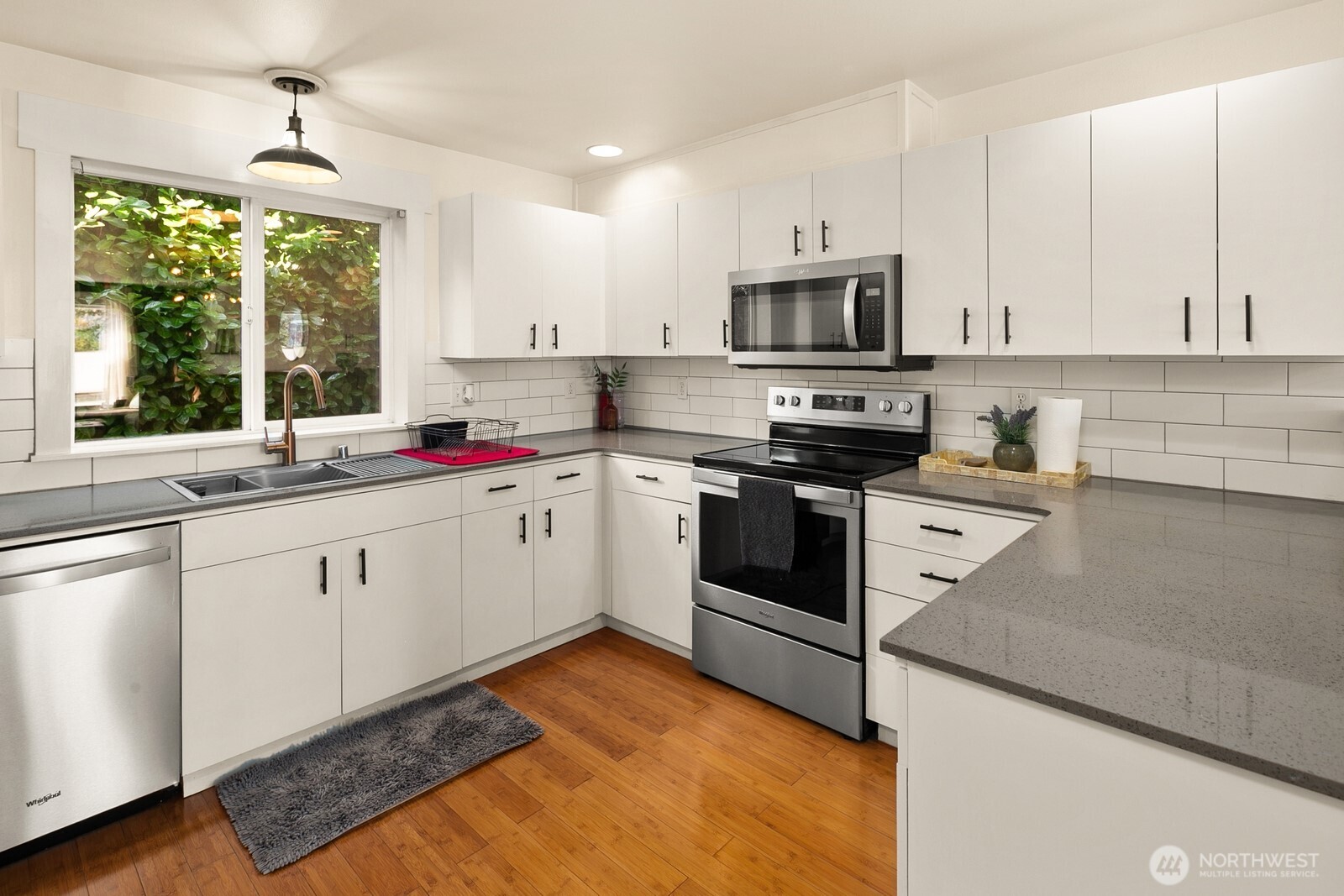 3224 21st Avenue West, Unit B Seattle, WA 98199 - Photo 6 of 17 a kitchen with stainless steel appliances granite countertop a sink dishwasher stove and white cabinets with wooden floor