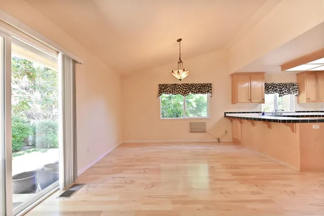 a view of a room with wooden floor chandelier and windows