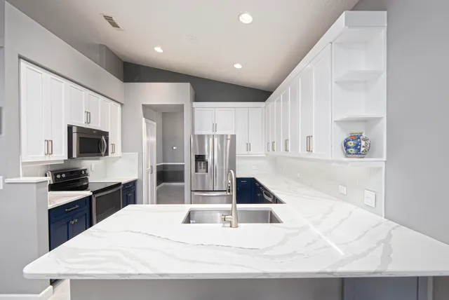 a large white kitchen with wooden floor and a refrigerator
