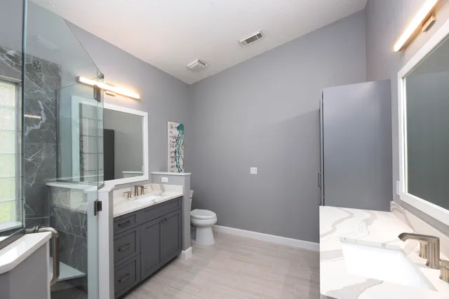 a bathroom with a double vanity sink mirror and toilet
