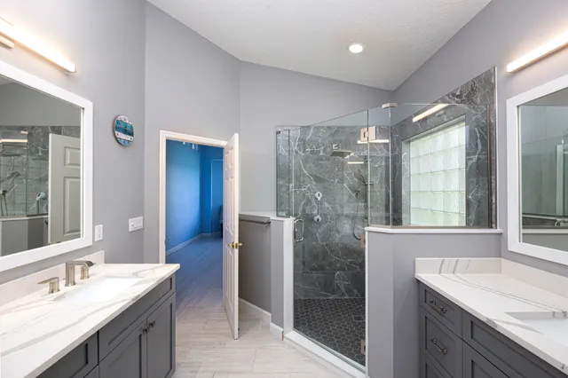 a bathroom with a granite countertop sink a large mirror and a shower