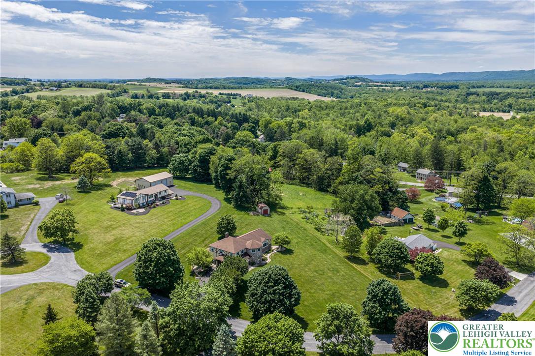 947 Tamenend Road Bath, PA 18014 - Photo 54 of 61 An aerial perspective reveals the vast green landscape surrounding multiple residential properties, highlighting expansive lots and mature trees.