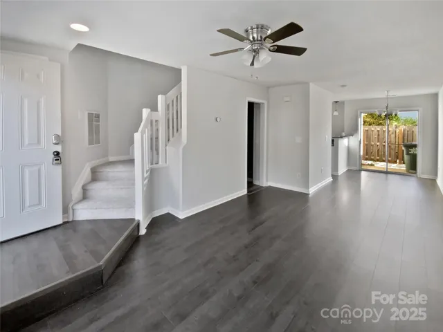 a view of an empty room with wooden floor and a ceiling fan