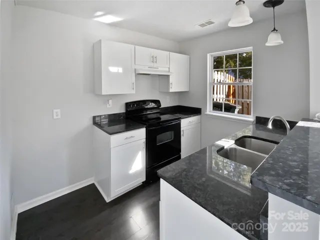 a kitchen with granite countertop a stove and a sink