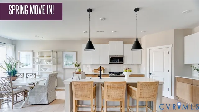 a kitchen with stainless steel appliances kitchen island granite countertop a dining table chairs and white cabinets