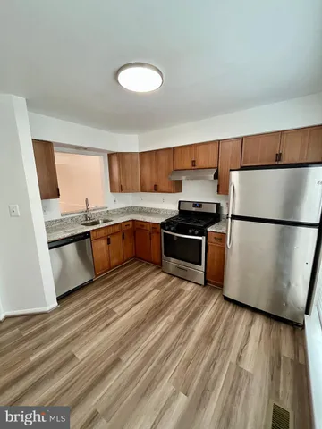 a kitchen with granite countertop a refrigerator a sink dishwasher stove and wooden cabinets