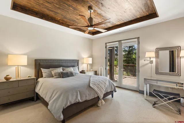 a spacious bedroom with a bed a chandelier and balcony