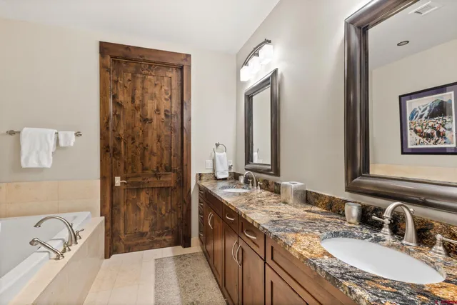 a bathroom with a granite countertop double vanity sink mirror and