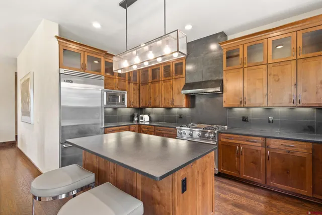 a kitchen with stainless steel appliances granite countertop a sink a stove and a refrigerator
