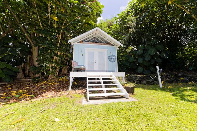 a view of house with backyard and trees in the background