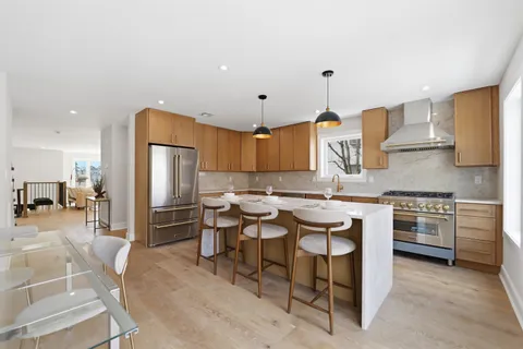 a kitchen with stainless steel appliances granite countertop a stove a sink a refrigerator and chairs