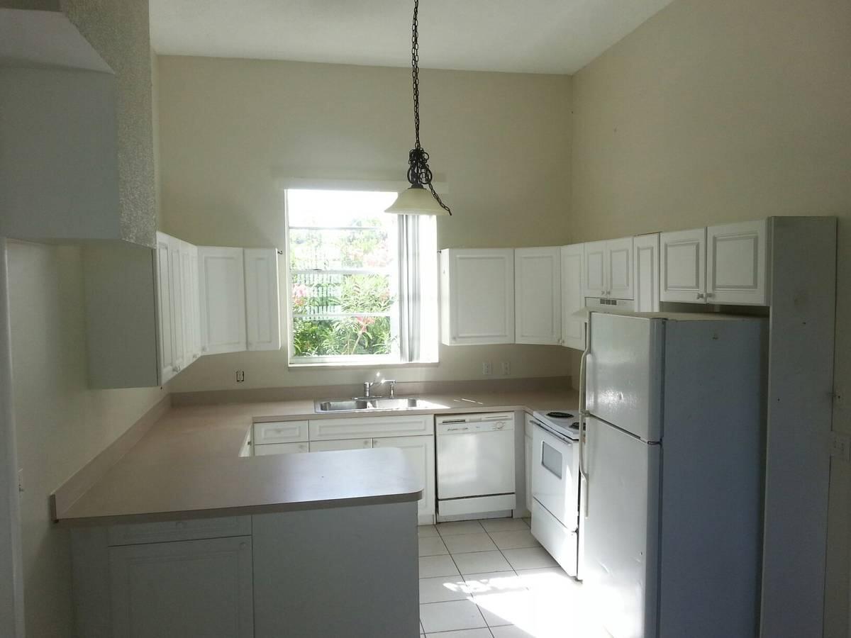 1140 Hernando Street Fort Pierce, FL 34949 - Photo 15 of 37 a kitchen with a sink a refrigerator a window and cabinets