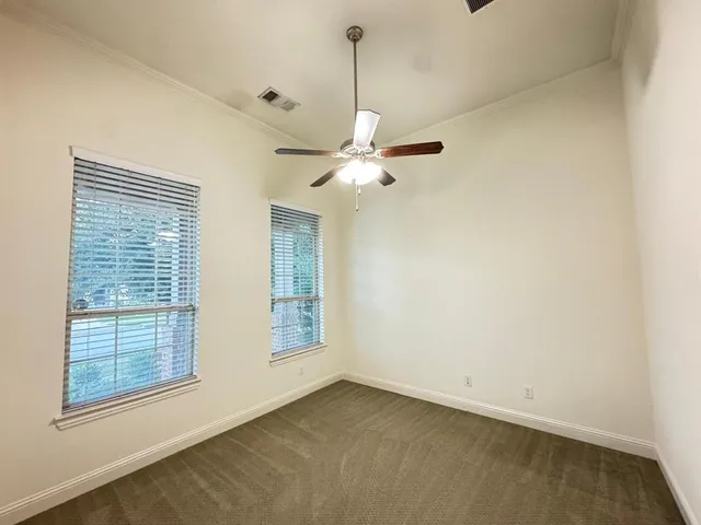 an empty room with a windows and ceiling fan