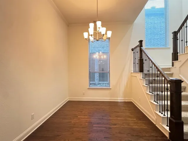 a view of a room with wooden floor chandeliers and kitchen view