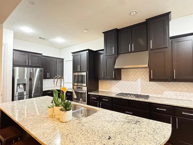 a kitchen with stainless steel appliances kitchen island granite countertop a refrigerator and stove
