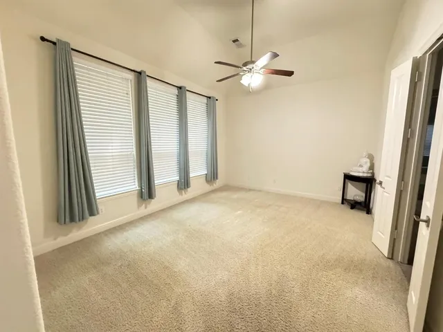 an empty room with windows and fan