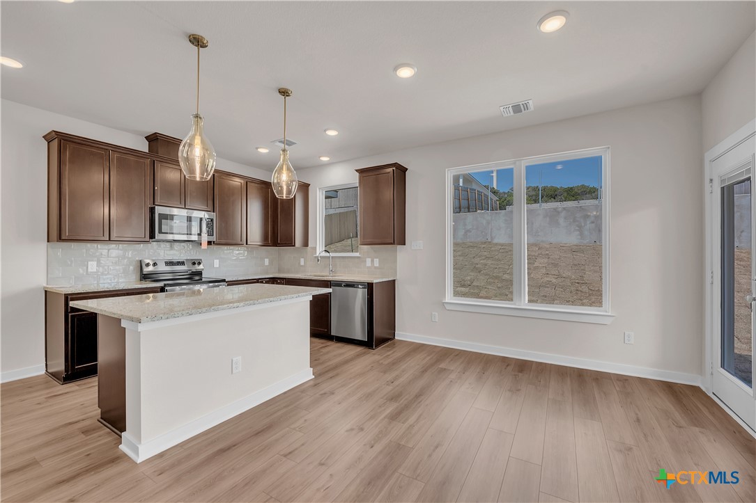 262 Wind Ridge Drive Copperas Cove, TX 76522 - Photo 19 of 30 a large kitchen with kitchen island granite countertop a sink cabinets and wooden floor