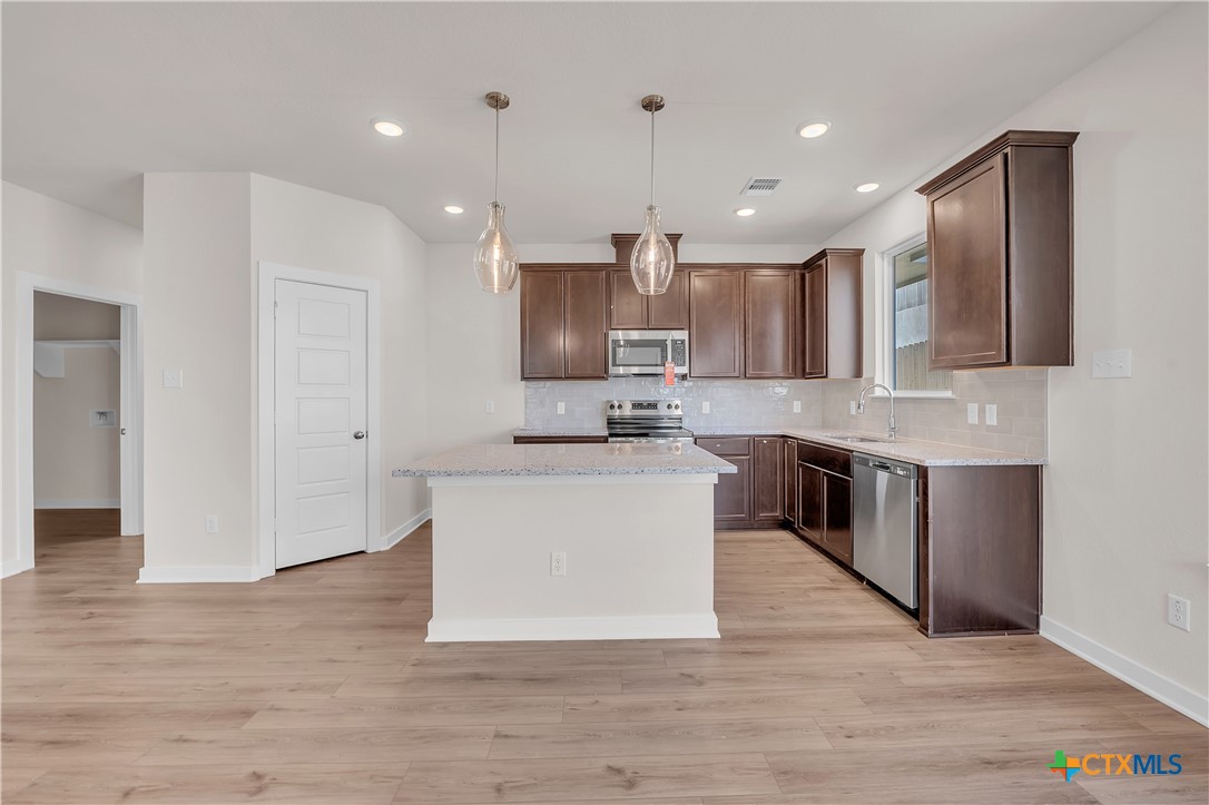 262 Wind Ridge Drive Copperas Cove, TX 76522 - Photo 20 of 30 a large kitchen with stainless steel appliances kitchen island a large counter top and a wooden floors