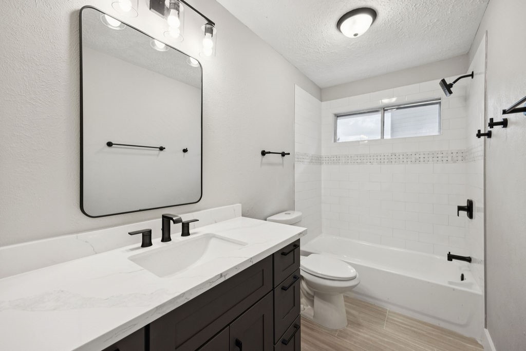 2942 Waterloo Road Pearland, TX 77581 - Photo 14 of 22 a bathroom with a granite countertop sink toilet a large mirror a bathtub and shower