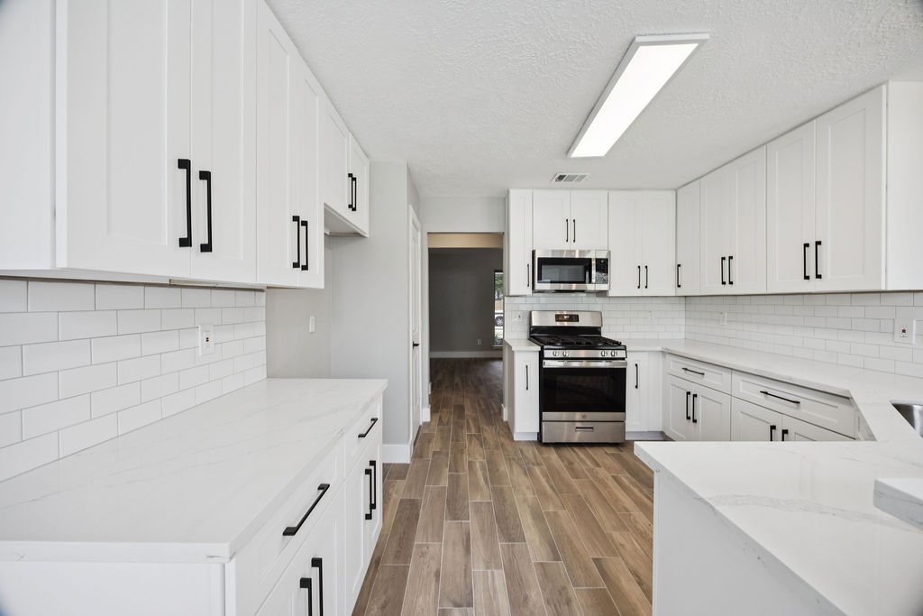 2942 Waterloo Road Pearland, TX 77581 - Photo 6 of 22 a kitchen with white cabinets and stainless steel appliances