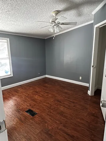 an empty room with wooden floor and fan
