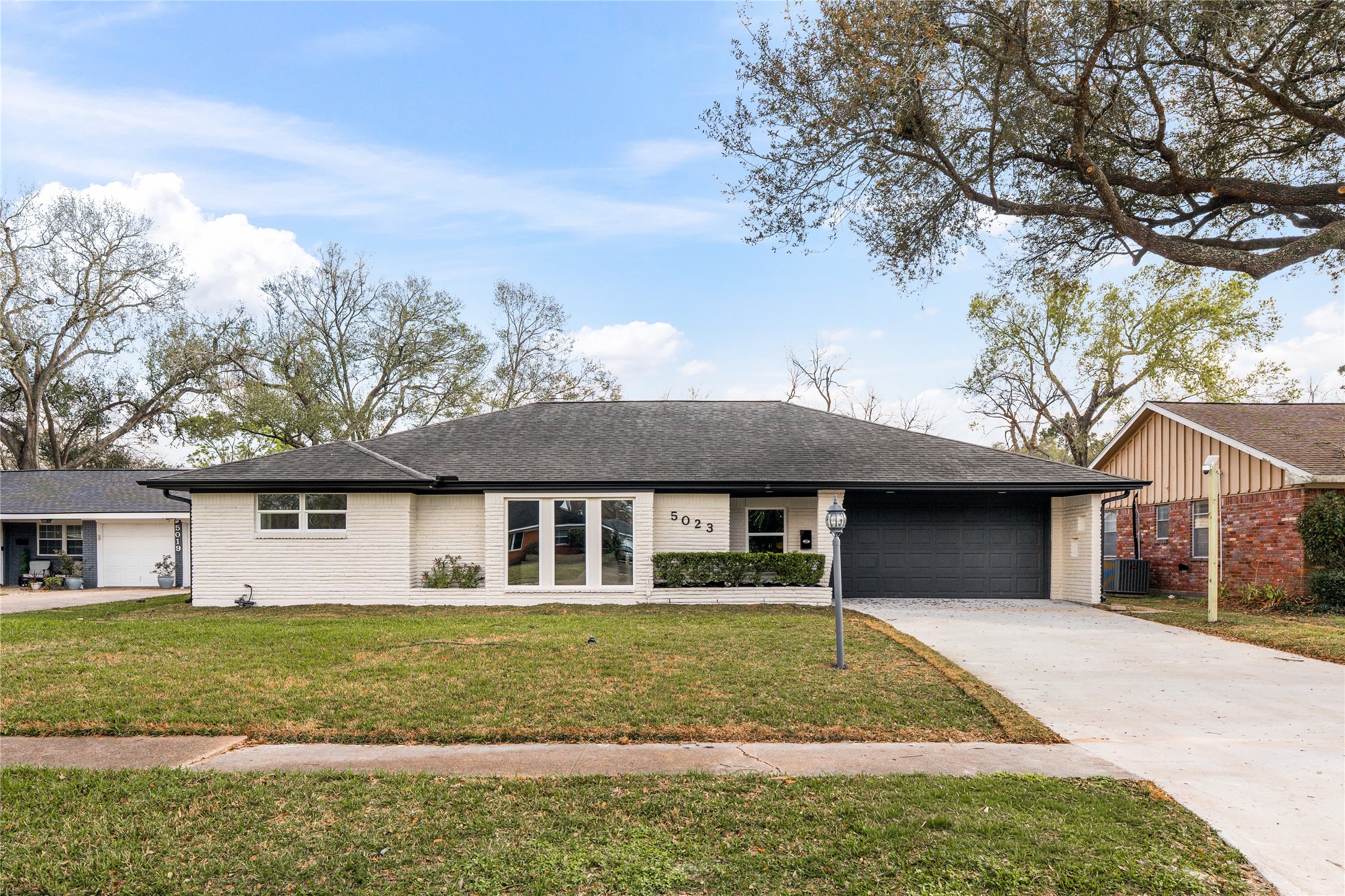 5023 Redstart Street Houston, TX 77035 - Photo 2 of 34 The wide paved driveway and minimalist landscaping highlight the home’s impressive width and clean, balanced architectural lines.