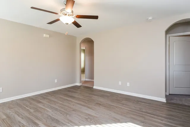 an empty room with wooden floor chandelier fan and closet area