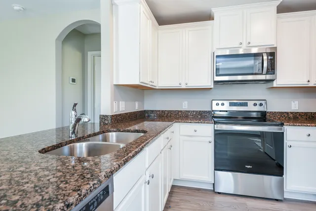 a kitchen with stainless steel appliances granite countertop a sink stove and cabinets