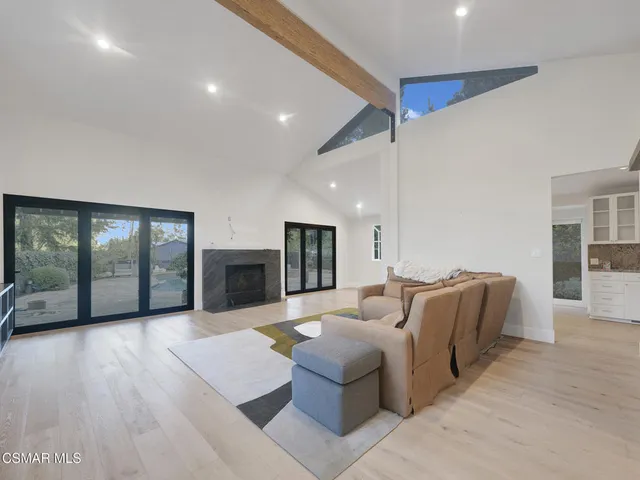 a living room with furniture large window and wooden floor