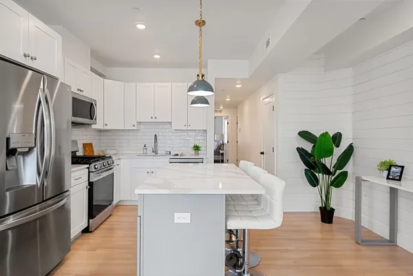 a kitchen with kitchen island a counter space a sink appliances and cabinets