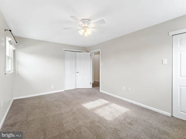 a view of an empty room with a chandelier fan