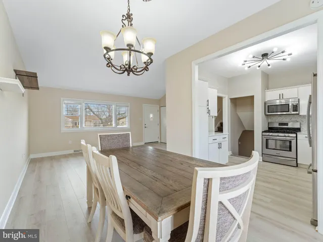a dining room with wooden floor a chandelier a wooden table and chairs