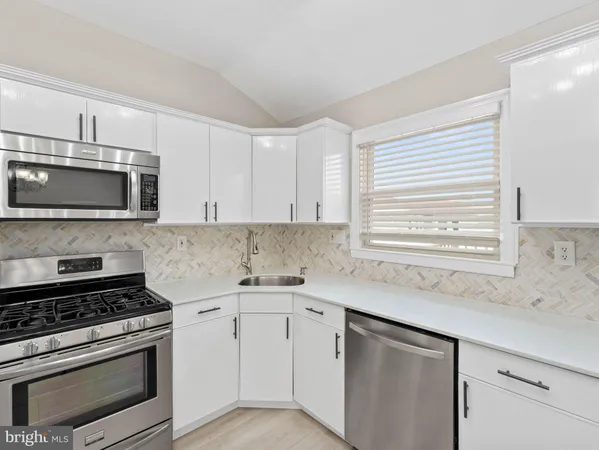 a kitchen with stainless steel appliances white cabinets and a stove top oven