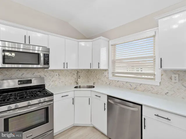 a kitchen with stainless steel appliances white cabinets and a stove top oven