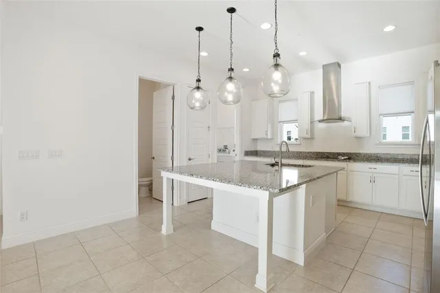 a large kitchen with granite countertop a sink and white cabinets