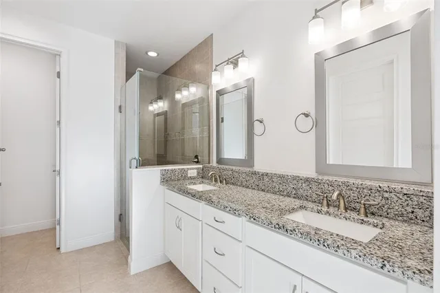 a bathroom with a granite countertop double vanity sink and a mirror