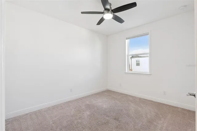 an empty room with a window and a fan