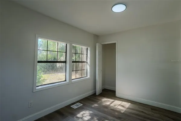 an empty room with wooden floor and windows