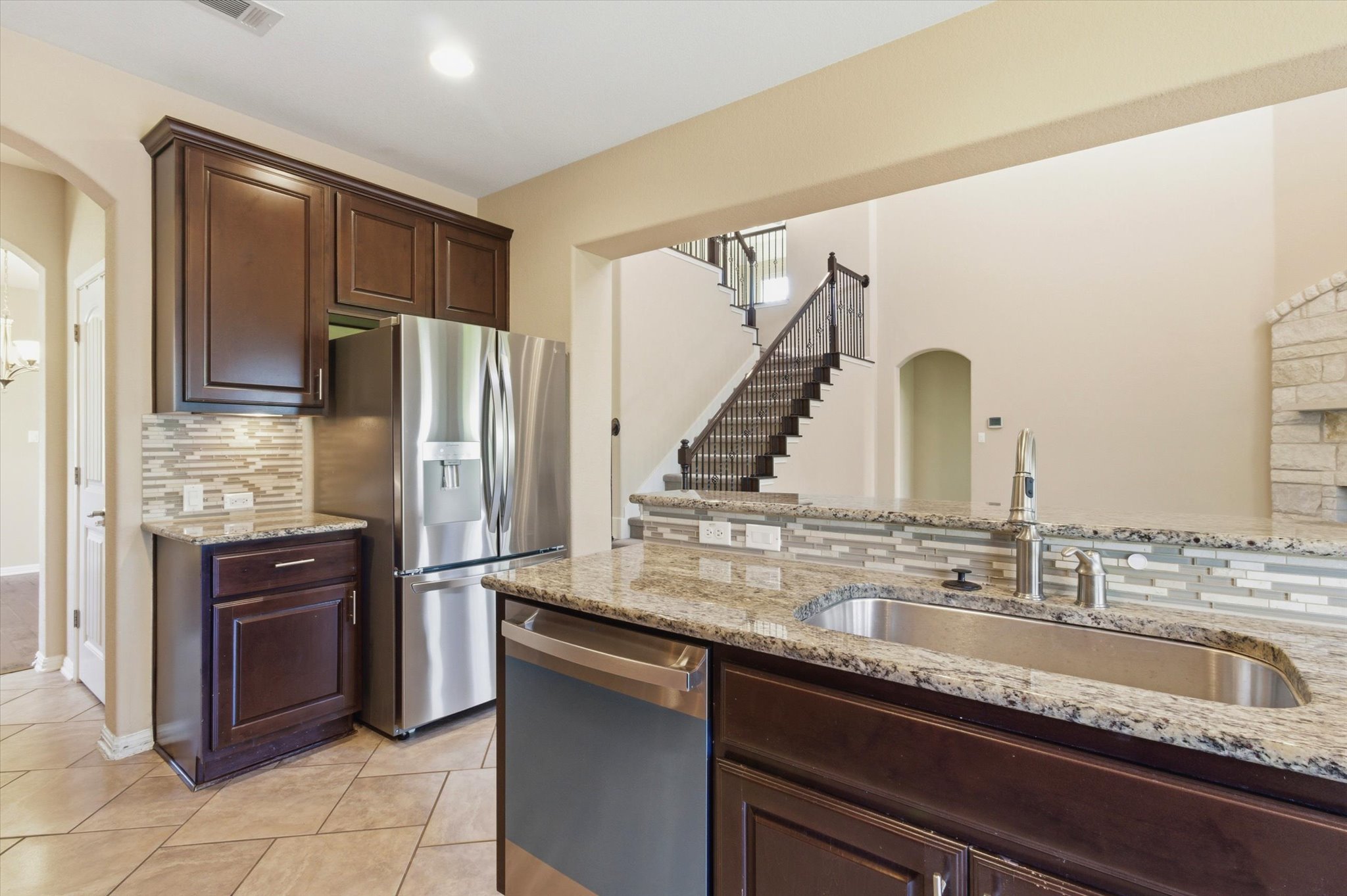 1511 Rimstone Drive Cedar Park, TX 78613 - Photo 10 of 39 Granite counters and stainless appliances define this open-concept kitchen, flowing into an inviting living space with a grand staircase.