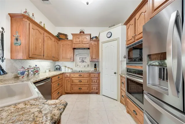 a kitchen with stainless steel appliances kitchen island granite countertop a refrigerator and a stove top oven
