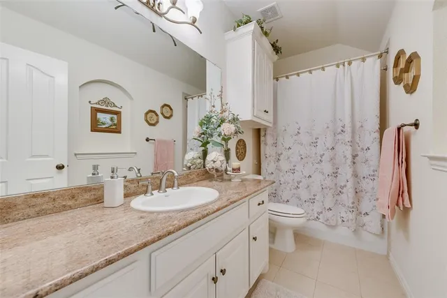 a bathroom with a granite countertop sink a toilet a mirror a vanity and shower